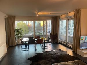 - un salon avec une table, des chaises et une grande fenêtre dans l'établissement Apartment in Heart of Brussel City with Balcony View, à Bruxelles