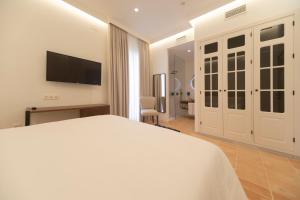 a bedroom with a white bed and a television at Albariza Hotel Boutique in Sanlúcar de Barrameda +130 photos