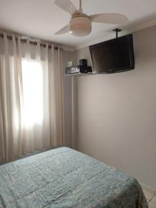 Schlafzimmer mit einem Bett und einem Flachbild-TV in der Unterkunft Quarto Aconchegante! in Sorocaba