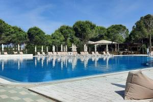 a large swimming pool with chairs and umbrellas at Super Villa for vacation Gjiri i Lalzit in Draç