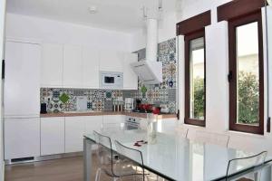 a white kitchen with a glass table and chairs at Super Villa for vacation Gjiri i Lalzit in Draç