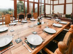 - une longue table en bois avec des assiettes et des verres à vin dans l'établissement Lee House Farm, à Halifax