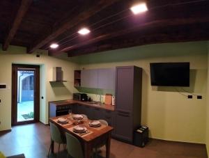 eine Küche mit einem Tisch mit Stühlen und einem TV in der Unterkunft La cascina della vigna del viandante in Abbadia Lariana