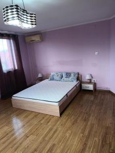 a bedroom with a bed and a purple wall at Apartament 2 dormitoare in Ploieşti
