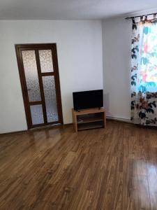 sala de estar con TV y suelo de madera en Apartament 2 dormitoare, en Ploieşti
