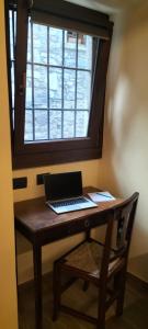 einen Laptop auf einem hölzernen Schreibtisch mit Fenster in der Unterkunft La cascina della vigna del viandante in Abbadia Lariana