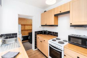 uma cozinha com armários de madeira e um forno com placa de fogão em Spacious 3 Bed House With Free Parking em Doncaster