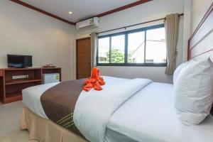 a bedroom with a large bed with an orange ribbon on it at Kata Noi Bay Inn in Kata Beach