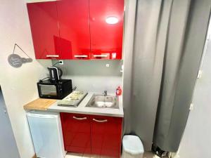 a small kitchen with a sink and red cabinets at Joli studio cosy, vue magnifique et terrasse privée in Gérardmer