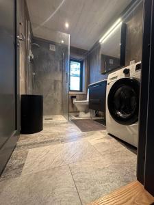 a bathroom with a washing machine and a shower at Helårs moderne familiehytte med wifi, billader, ski inn, ski ut og utmerket beliggenhet in Drangedal