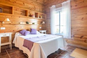 1 dormitorio con paredes de madera y 1 cama con almohadas moradas en Casa de Madera del Turullote, en Écija