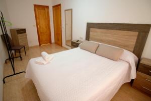 1 dormitorio con 1 cama blanca grande y cabecero de madera en Luna de Garrucha, en Garrucha