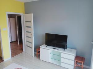 a living room with a flat screen tv on a dresser at Apartament4U - Olimpijskie Ogrody in Suwałki
