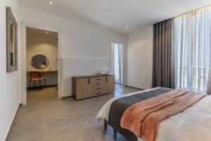 a bedroom with a bed and a dresser and a mirror at Private Penthouse with Heated Spa Bath Pembroke St Julians in Pembroke