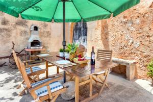 a wooden table with chairs and a green umbrella at Casa Antigua in Santanyi