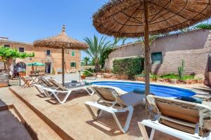 a group of chairs and an umbrella next to a pool at Casa Antigua in Santanyi