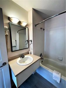 a bathroom with a sink and a mirror and a tub at Super 8 by Wyndham Lake Country/Winfield Area in Winfield
