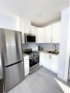 a kitchen with white cabinets and a stainless steel refrigerator at Super 8 by Wyndham Lake Country/Winfield Area in Winfield