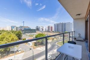 uma varanda com uma mesa branca e vista para a cidade em Lovely 1 BDR Apartment With Pool by LovelyStay em Lisboa