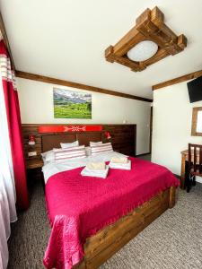 1 dormitorio con cama de madera y manta roja en SPA & WELLNESS Penzión Zorhill, en Ždiar