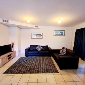 a living room with a couch and a tv at Villa 2 Pool Spa Beach Sea! in Mandurah