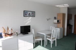 ブラズィリアンにあるFerienappartement K312 für 2-3 Personen in Strandnäheのテーブル、テレビ、テーブルと椅子が備わる客室です。