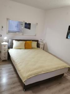 1 dormitorio con 1 cama grande con almohadas amarillas en Apartman Enio en Vukovar