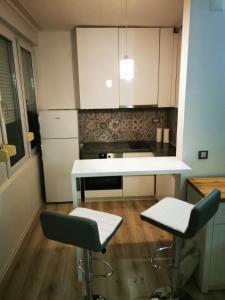 a kitchen with a table and two stools in it at Apartman Enio in Vukovar