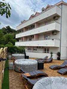 a large building with lounge chairs in front of it at APARTMANI SABB in Jezera