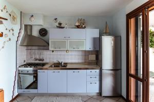 Una cocina con gabinetes blancos y un refrigerador de acero inoxidable. en la "PERLA", con vista sul Lago di Garda, en Padenghe sul Garda