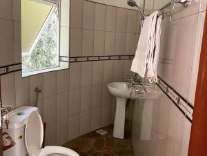 łazienka z umywalką, toaletą i oknem w obiekcie Rafiki Safari Lodge Bwindi w mieście Kinkizi