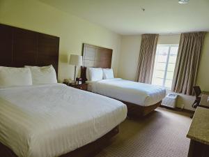 a hotel room with two beds and a window at Cobblestone Inn & Suites - Bloomfield in Bloomfield
