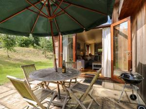 a patio with a table and chairs and an umbrella at Tickencote in Cottesmore