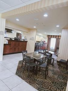 a dining room with tables and chairs and a kitchen at Cobblestone Inn & Suites - Bloomfield in Bloomfield