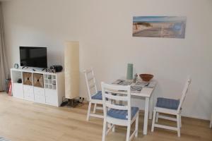 uma sala de estar com uma mesa e uma televisão e cadeiras em Ostseeappartement K014 em Brasilien