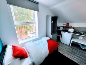 a bedroom with a bed with red pillows and a window at Berridge Solo Stays - NG7 in Nottingham