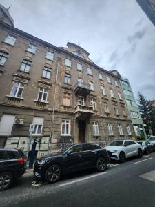 a large building with cars parked in front of it at Maksuzija in Sarajevo