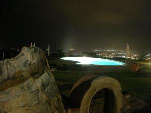 a swimming pool at night with a city in the background at Agriturismo Mercurio in Campiglia Marittima