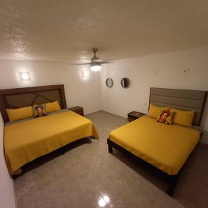 two beds in a room with yellow sheets at Condos Frida in Cozumel