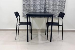 a black table and two chairs in front of a wall at Bigson Service Apartments Gachibowli in Hyderabad