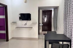 a living room with a table and a tv on a wall at Bigson Service Apartments Gachibowli in Hyderabad