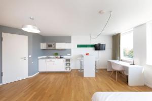 a white room with a kitchen and a desk at Brera Serviced Apartments Nürnberg in Nuremberg