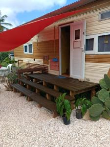 ein Haus mit einer Holzveranda mit rotem Dach in der Unterkunft Backpack Cabin A 49149 in Oranjestad