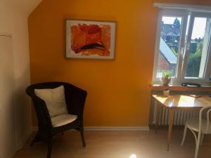 Zimmer mit einem Stuhl, einem Tisch und einem Gemälde in der Unterkunft Glück in Benrath in Düsseldorf