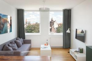 - un salon avec un canapé et 2 grandes fenêtres dans l'établissement Brera Serviced Apartments Nürnberg, à Nuremberg