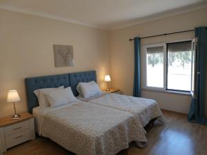 a bedroom with a bed with a blue headboard and a window at Herdade do Montinho in Portalegre