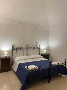 1 dormitorio con 1 cama con sábanas azules y 2 mesas en Rinaldo Holiday Home, en Sambuca di Sicilia
