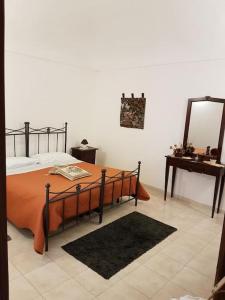 1 dormitorio con cama, espejo y mesa en Rinaldo Holiday Home, en Sambuca di Sicilia