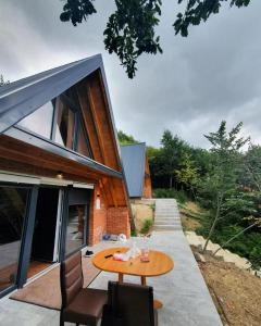 Cette maison dispose d'une terrasse avec une table et des chaises en bois. dans l'établissement Dawn Villas, à Ferizaj