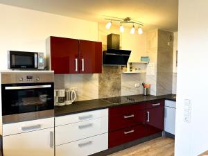 a kitchen with red and white cabinets and a microwave at A703, schöne und große Ferienwohnung in Lahnstein